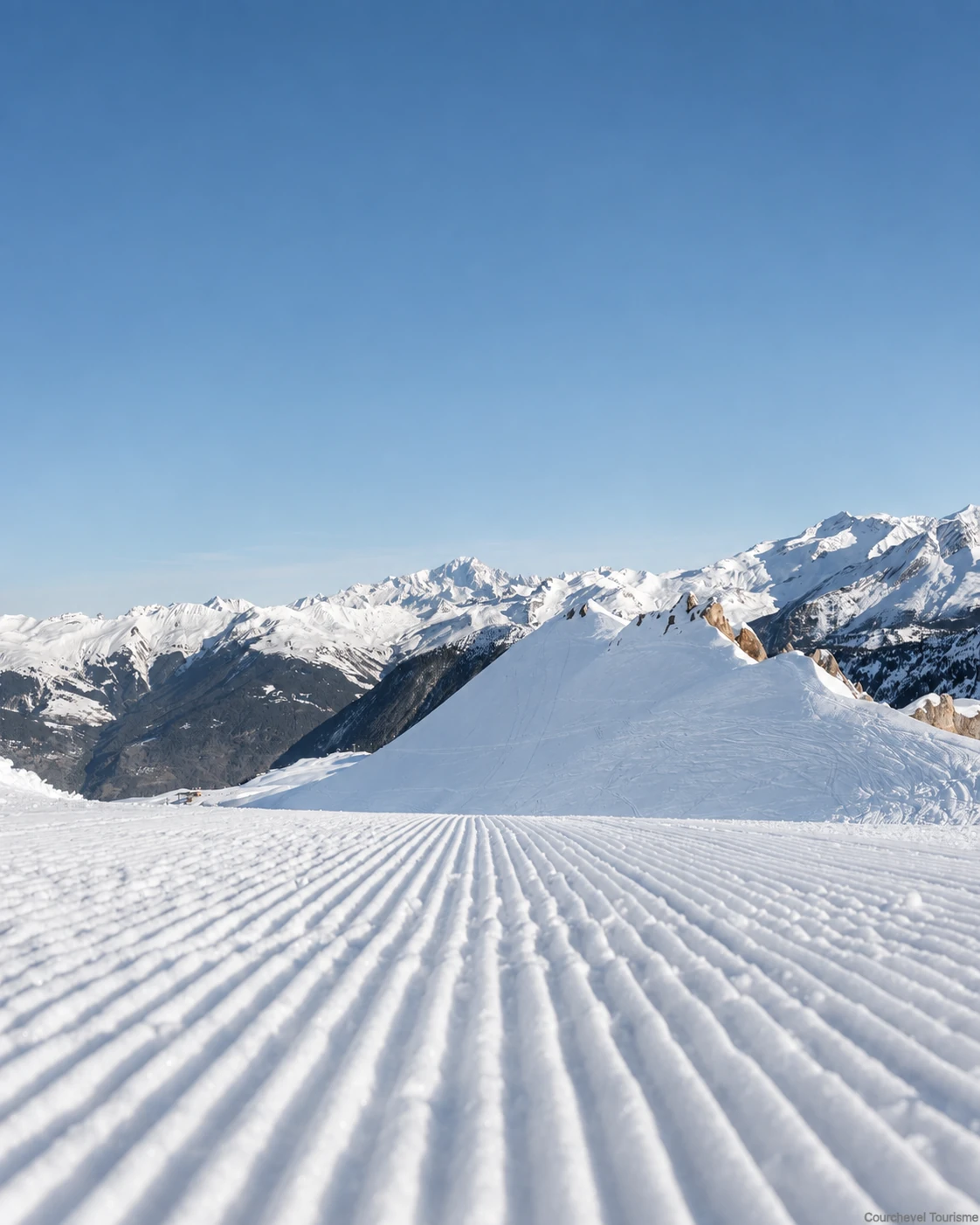 Piste fraîchement damée face aux sommets enneigés de Courchevel